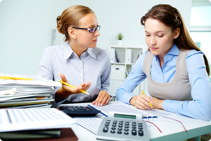Portrait of young businesswomen interacting while working with papers in office
